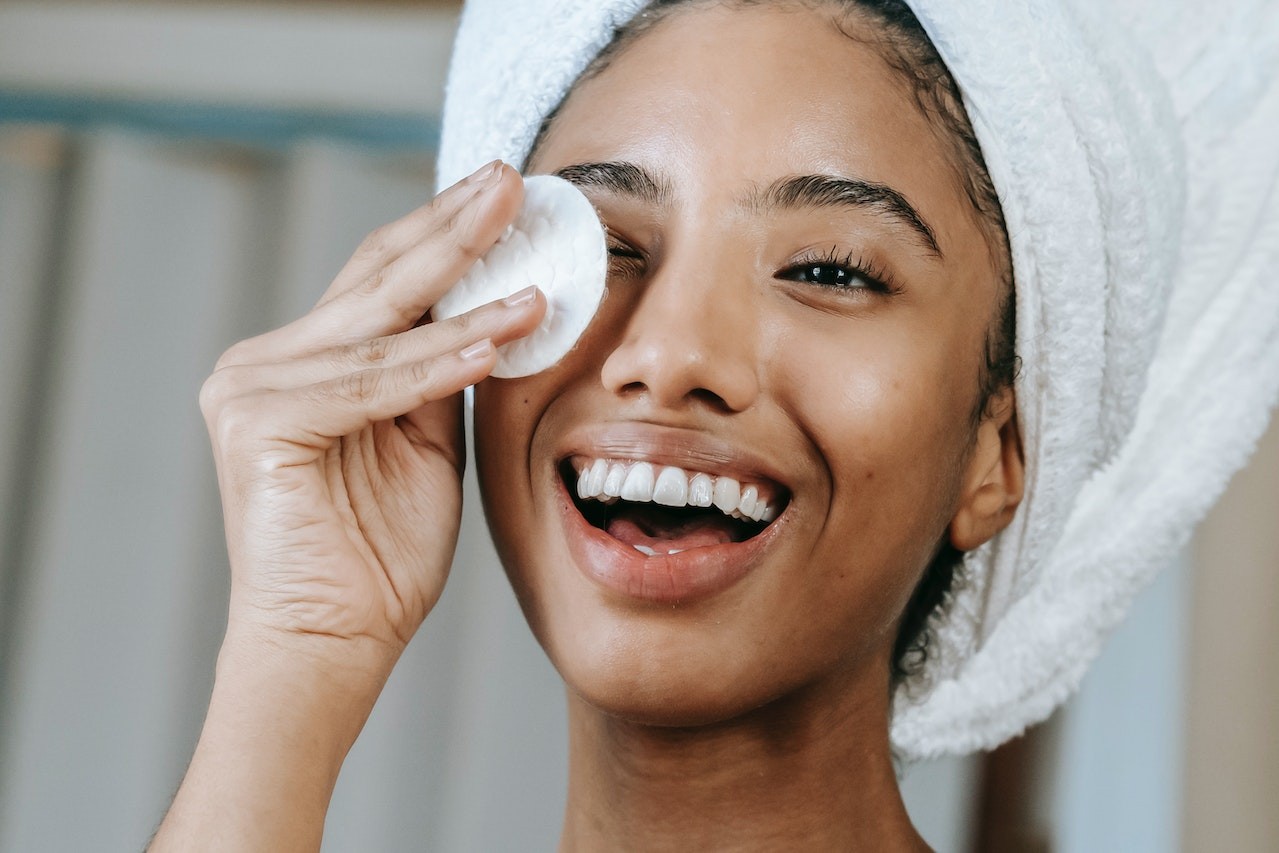 lady with towel on her head wiping her face with a pod