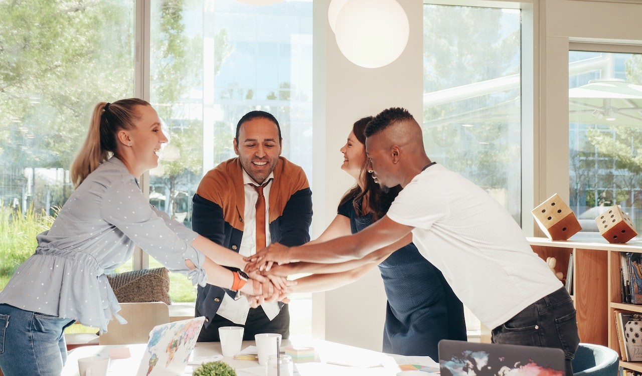 4 employess with their hands in a group in the middle